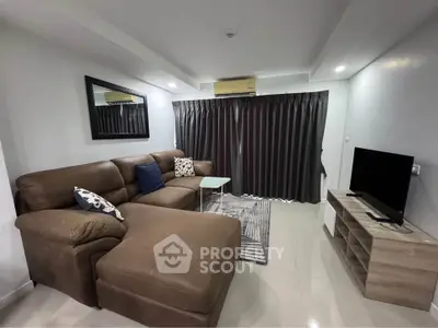 Modern living room with brown sectional sofa, TV, and stylish decor in a cozy apartment.