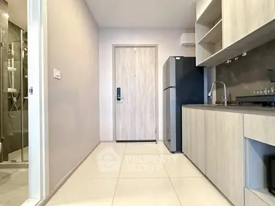 Modern kitchen with sleek cabinetry and stainless steel appliances in a compact apartment setting.