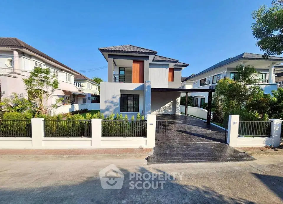 Modern two-story house with sleek design and spacious driveway in a suburban neighborhood.