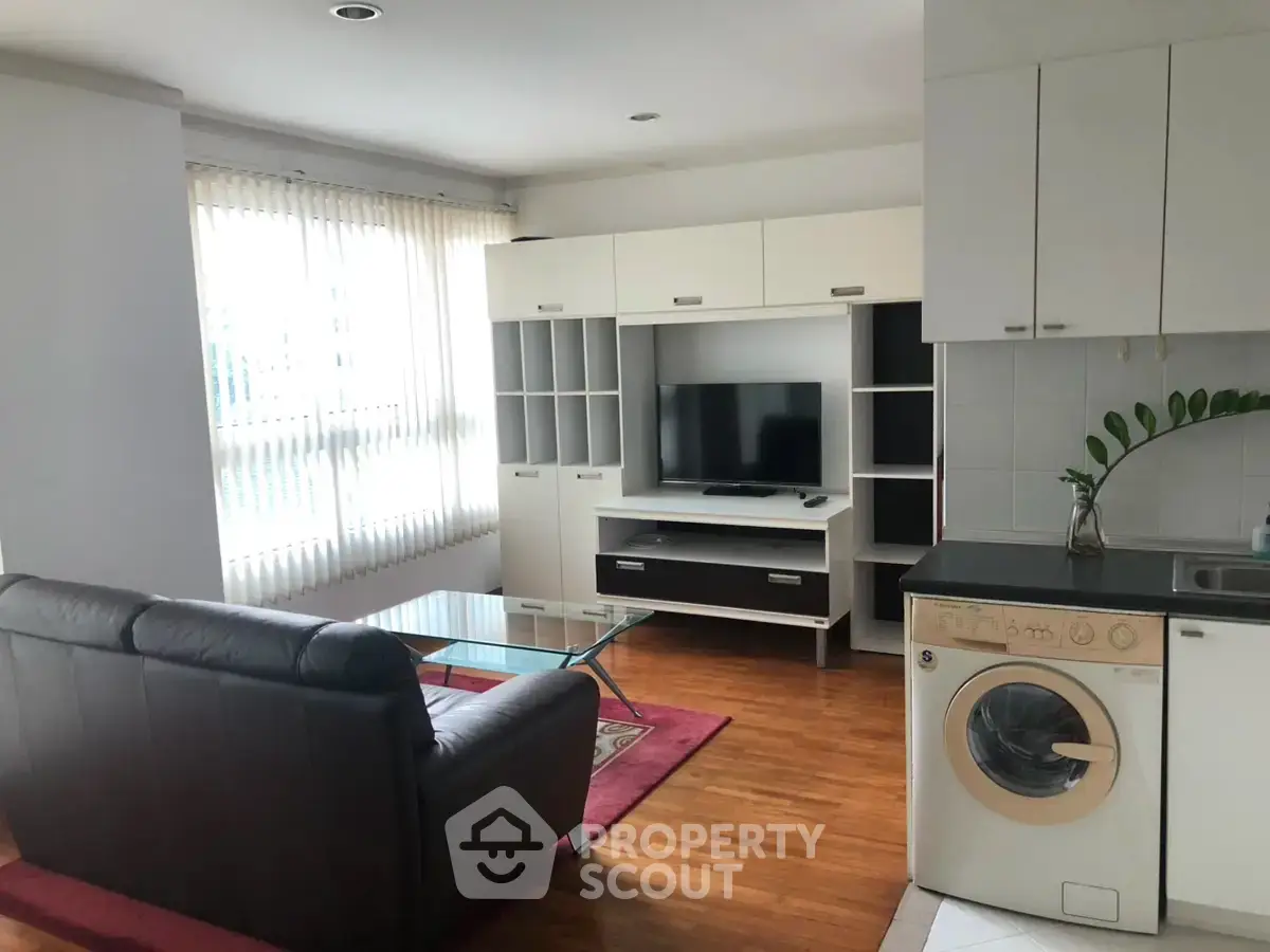 Modern living room with washing machine and sleek furniture in open layout.