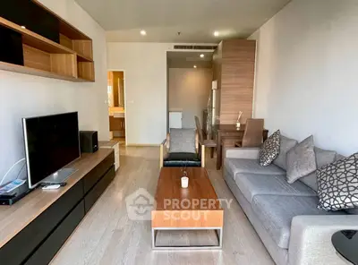 Modern living room with sleek furniture and open layout, featuring a cozy sofa and entertainment center.