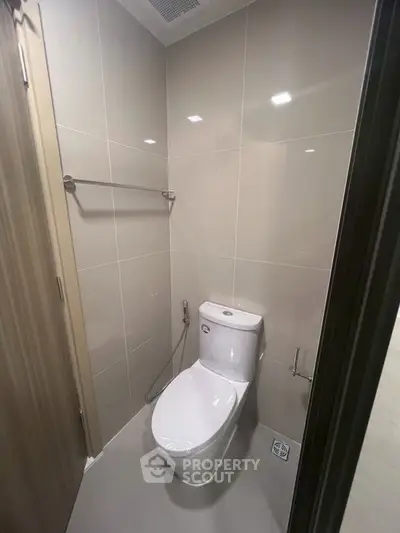 Modern bathroom with sleek toilet and tiled walls in a compact space.