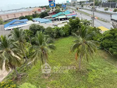 Prime land plot with lush greenery and palm trees, ideal for development, located near bustling commercial area.
