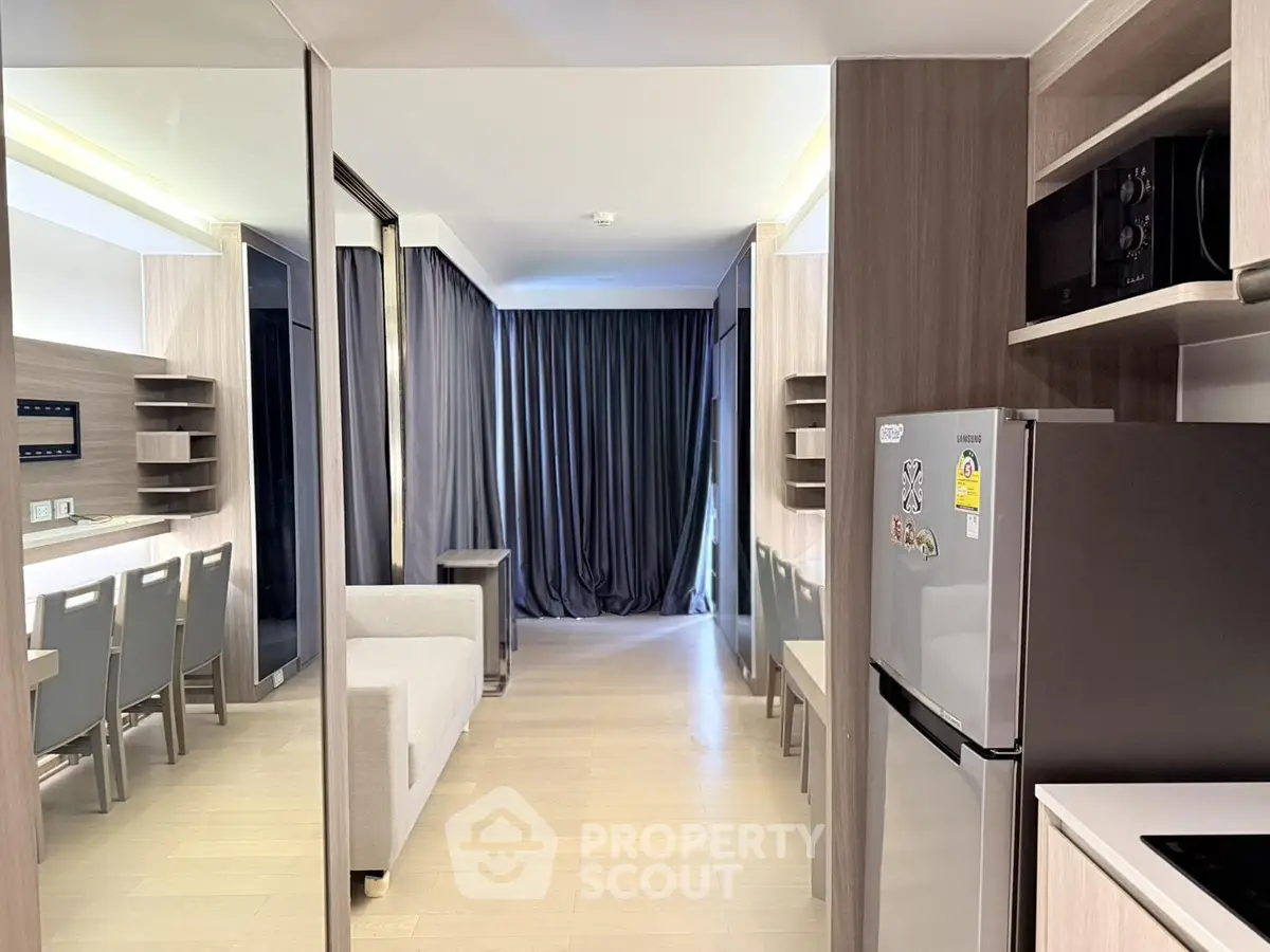 Modern open-layout apartment with sleek kitchen and cozy living area, featuring stylish furniture and ample natural light.