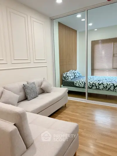 Modern living room with elegant decor and cozy seating adjacent to a stylish bedroom.