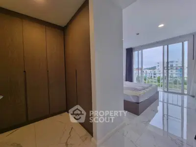 Modern bedroom with large windows and built-in closet offering a serene view.