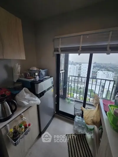 Cozy kitchen with balcony offering city view, compact appliances, and modern decor.
