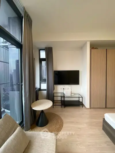 Modern living room with stylish furniture and large windows offering city views.