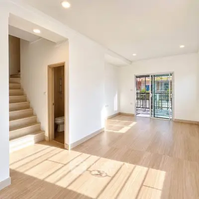 Spacious sunlit living room with wooden flooring and balcony access in modern home.