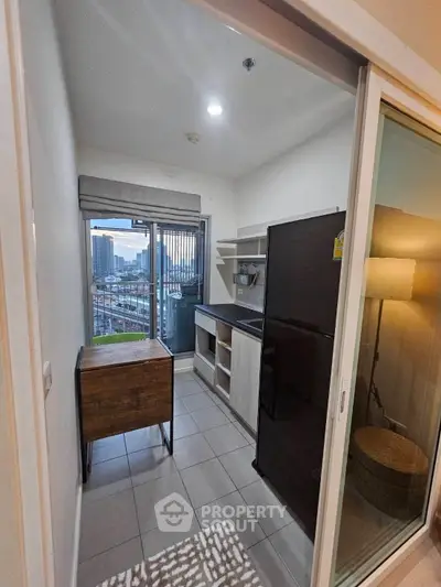 Modern compact kitchen with city view, featuring sleek appliances and ample natural light.