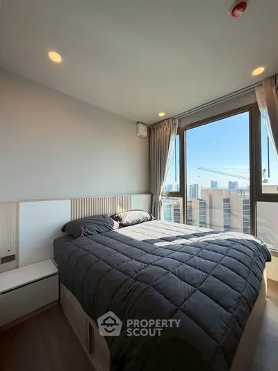 Modern bedroom with large window offering stunning city views, featuring cozy bedding and sleek design.
