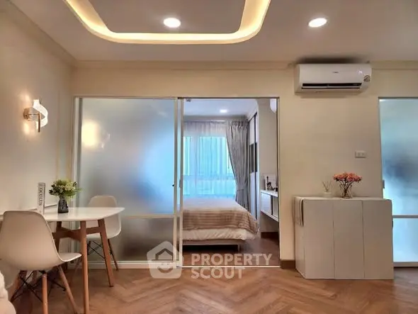 Modern apartment interior with cozy bedroom and stylish dining area, featuring elegant lighting and wooden flooring.
