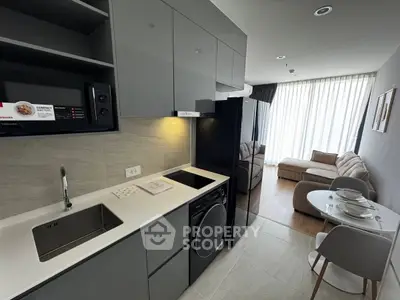 Modern open-layout kitchen with sleek appliances and cozy living area in a stylish apartment.