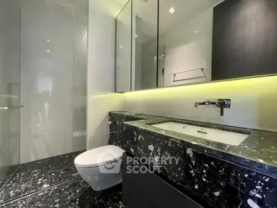 Luxurious modern bathroom with sleek black marble finishes and elegant lighting.