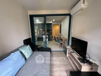 Modern living room with cozy sofa and TV, open layout to dining area and kitchen.