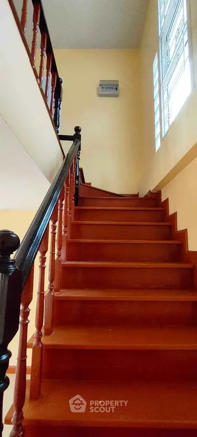 Charming wooden staircase with elegant railing in a well-lit interior space