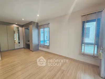 Spacious modern bedroom with wooden flooring and large windows