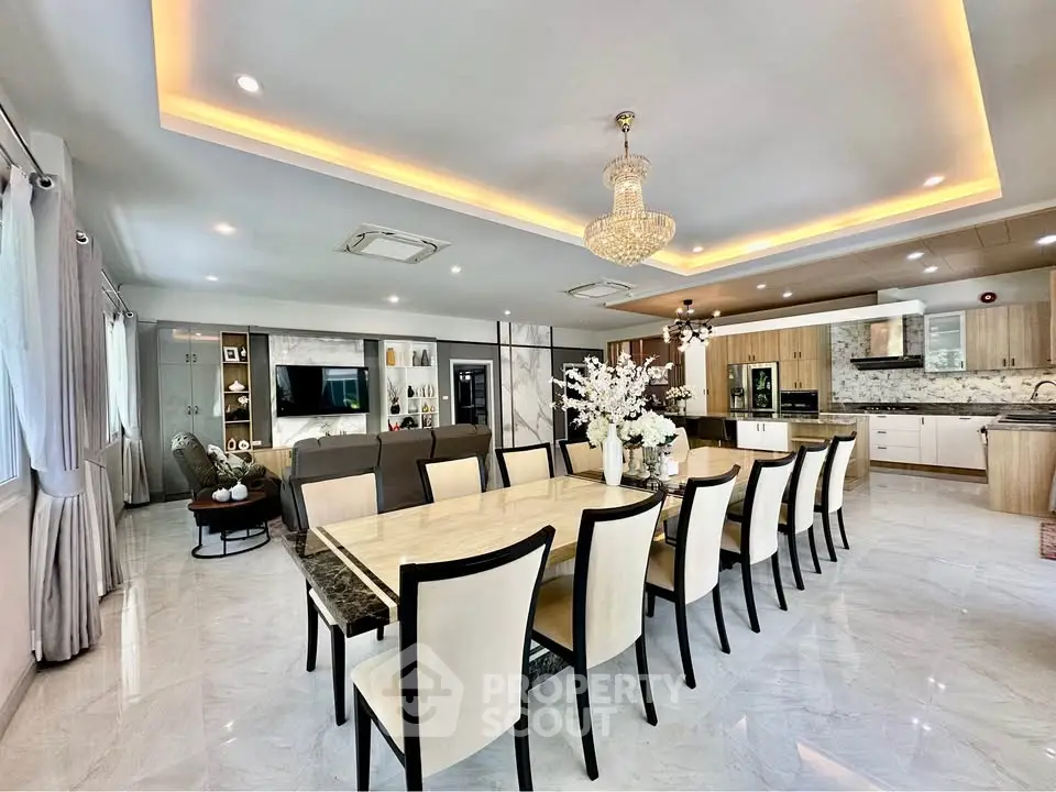 Luxurious open-plan living and dining area with elegant chandelier and modern kitchen.