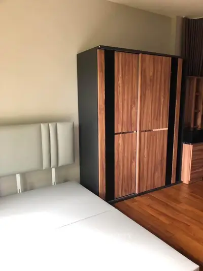 Modern bedroom with stylish wooden wardrobe and sleek bed frame.