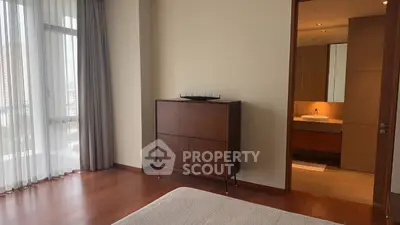 Modern bedroom with wooden flooring and ensuite bathroom in luxury apartment