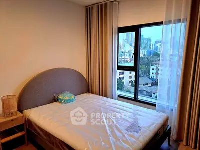 Cozy bedroom with city view, featuring a comfortable bed and large window for natural light.