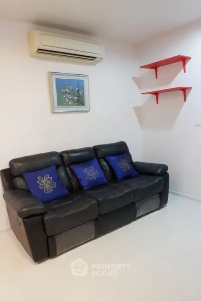 Cozy living room with black leather sofa and air conditioning