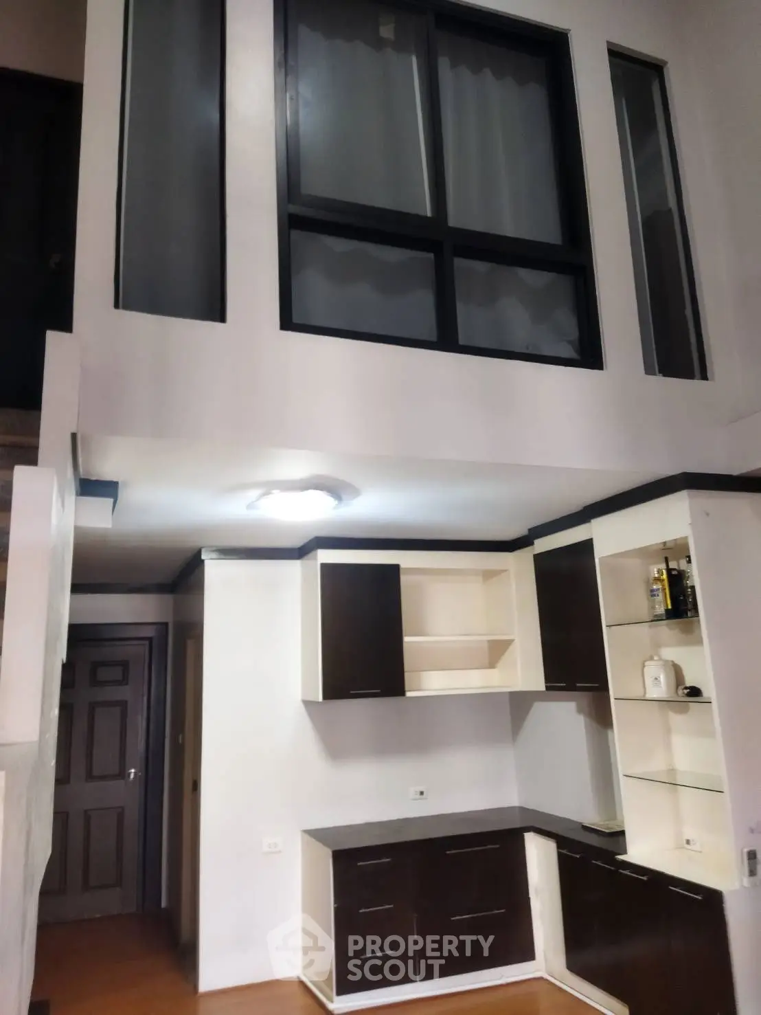 Modern kitchen with high ceiling and sleek cabinetry in a stylish apartment.