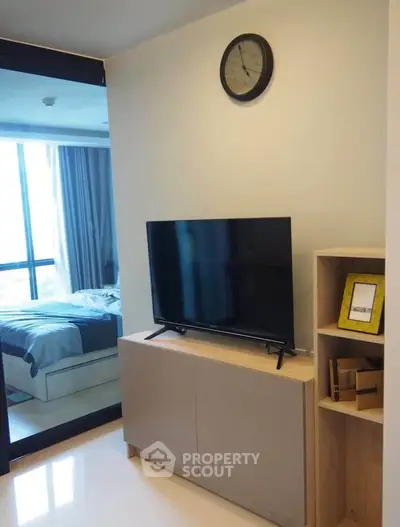 Modern apartment interior with TV and bedroom view, featuring sleek design and natural light.