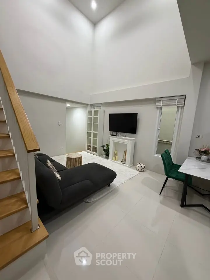 Modern living room with high ceiling, sleek staircase, and stylish decor