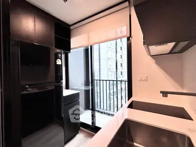 Modern kitchen with sleek black cabinetry and balcony view in urban apartment