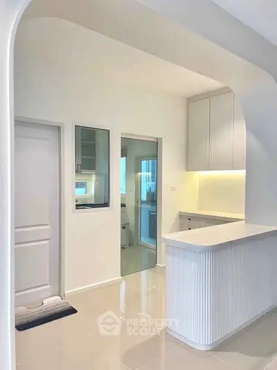 Modern kitchen with sleek design and open layout, featuring glossy floors and ambient lighting.
