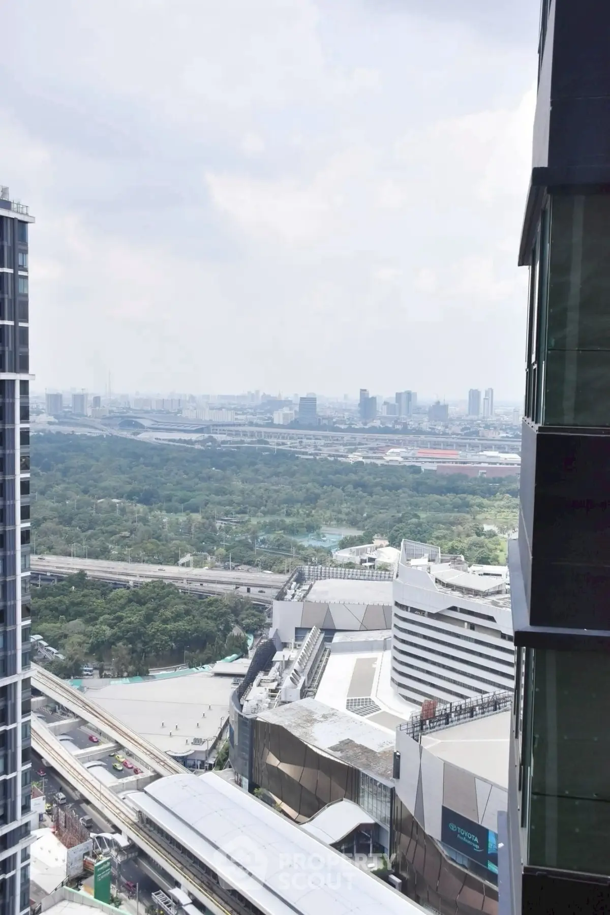 Stunning cityscape view from high-rise building with lush greenery and urban skyline.