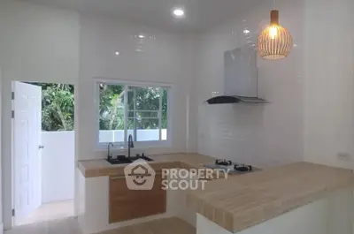 Modern kitchen with open layout, wooden countertops, and stylish lighting in a bright home.