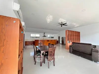 Spacious open-plan living room with dining area and modern kitchen, featuring high ceilings and ample natural light.