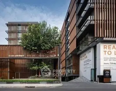 Modern apartment building exterior with sleek design and lush greenery.