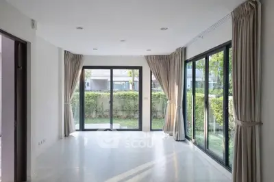 Spacious corner unit living room with large windows and garden view