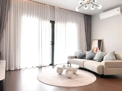 Elegant living room with modern sofa, stylish chandelier, and large windows with sheer curtains.