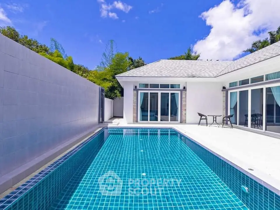 Luxurious modern villa with private pool and spacious patio under clear blue skies.