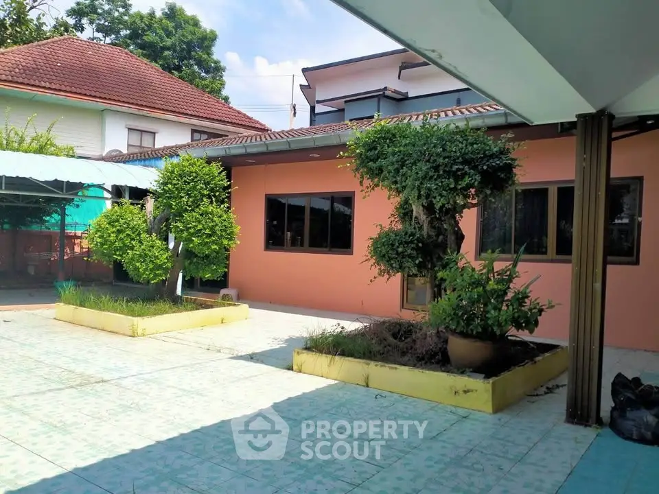 Charming courtyard with lush greenery and spacious tiled patio in a serene residential setting.