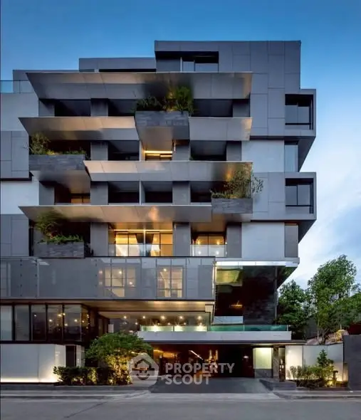 Modern architectural building with unique geometric facade and lush greenery.