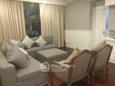 Elegant living room with plush gray sofas and classic armchairs, perfect for cozy gatherings.