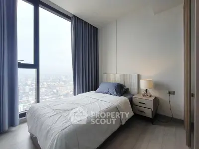 Modern bedroom with city view, featuring cozy bed and stylish decor.