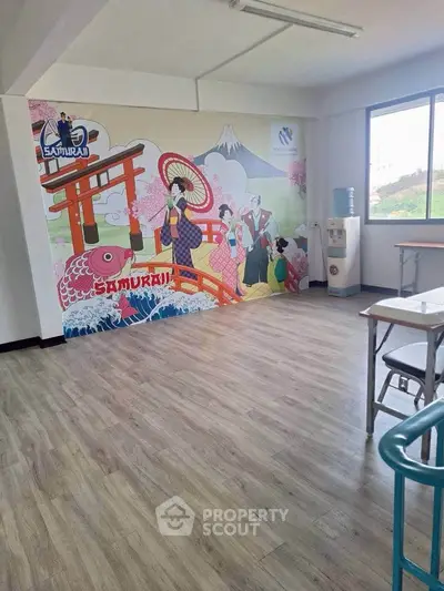 Spacious room with vibrant Samurai-themed wall art and large window offering natural light.