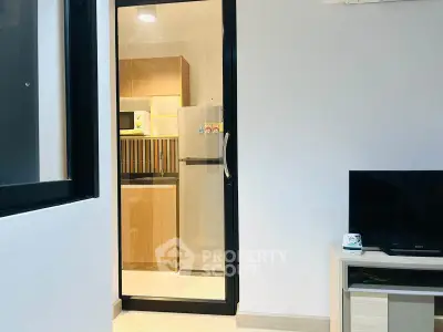 Modern apartment with sleek kitchen and cozy living area, featuring a fridge and microwave.