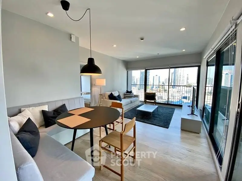 Modern living room with city view, stylish furniture, and ample natural light.