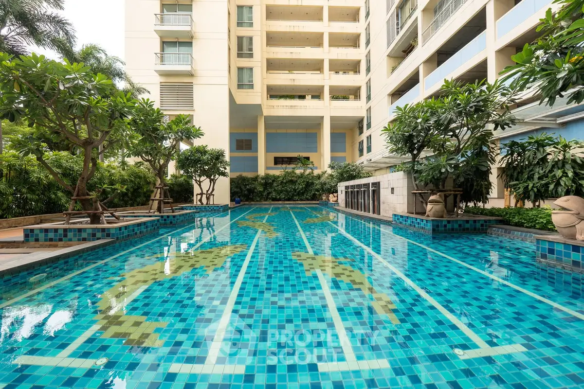 Luxurious residential building with a stunning outdoor swimming pool surrounded by lush greenery.