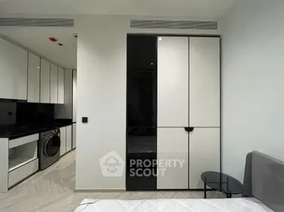 Modern bedroom with sleek built-in wardrobe and compact kitchen area.