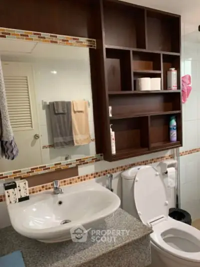 Modern bathroom with stylish vanity and shelving, featuring elegant tile accents and contemporary fixtures.