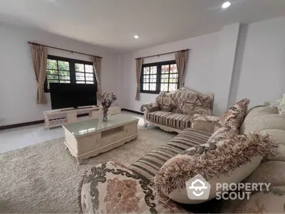 Elegant living room with plush sofas and large windows in a cozy home setting.