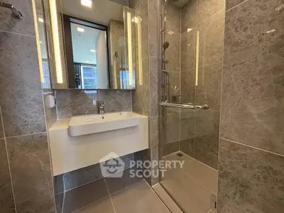 Modern bathroom with sleek design and glass shower enclosure in luxury apartment.